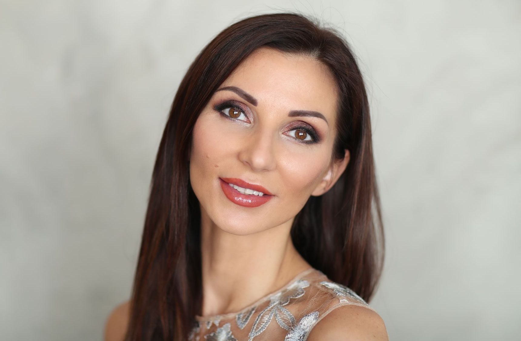 A woman with long brown hair is smiling and looking up at the camera.