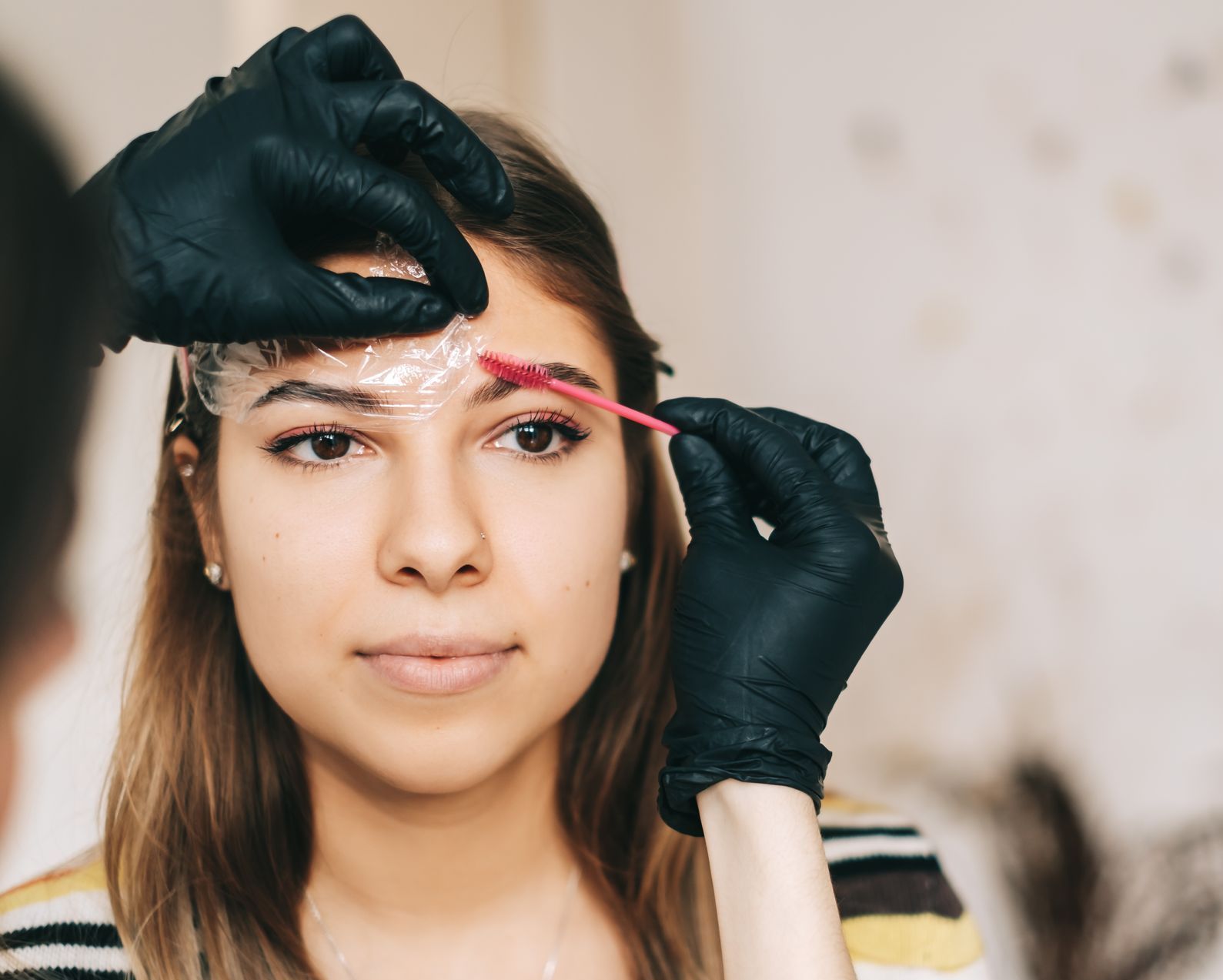 A woman is getting her eyebrows dyed in a salon.