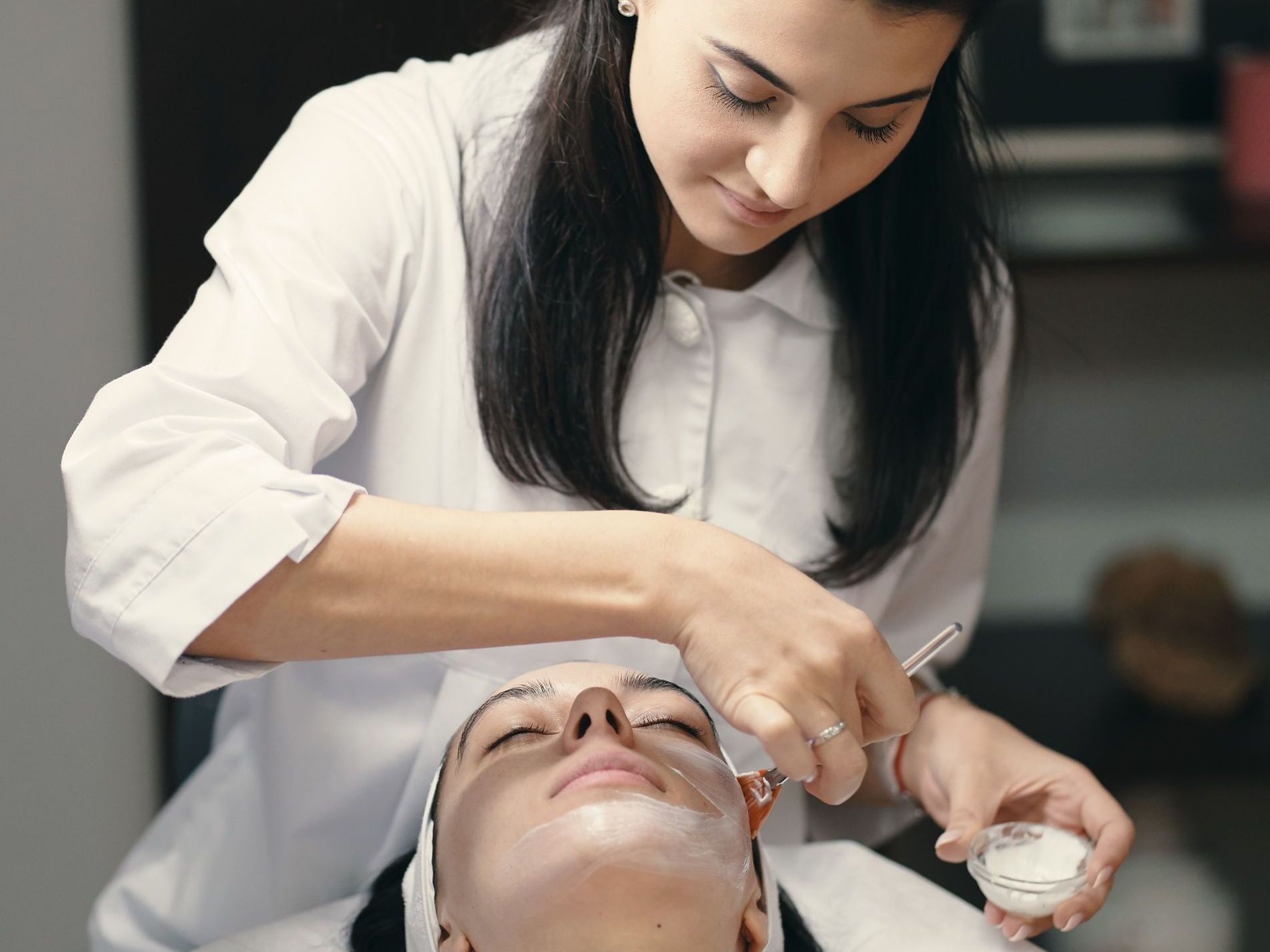 A young woman is wearing a green clay mask on her face.