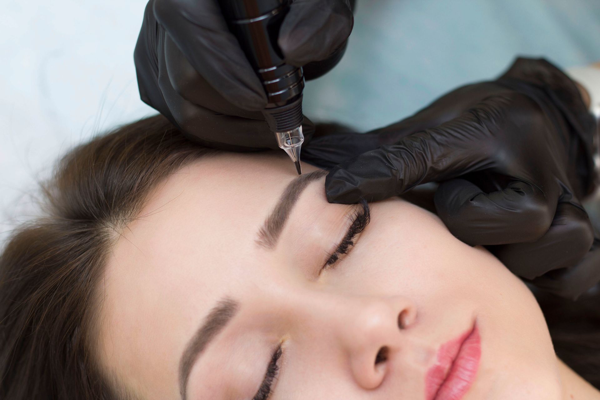 A woman is getting a permanent makeup tattoo on her eyebrows.