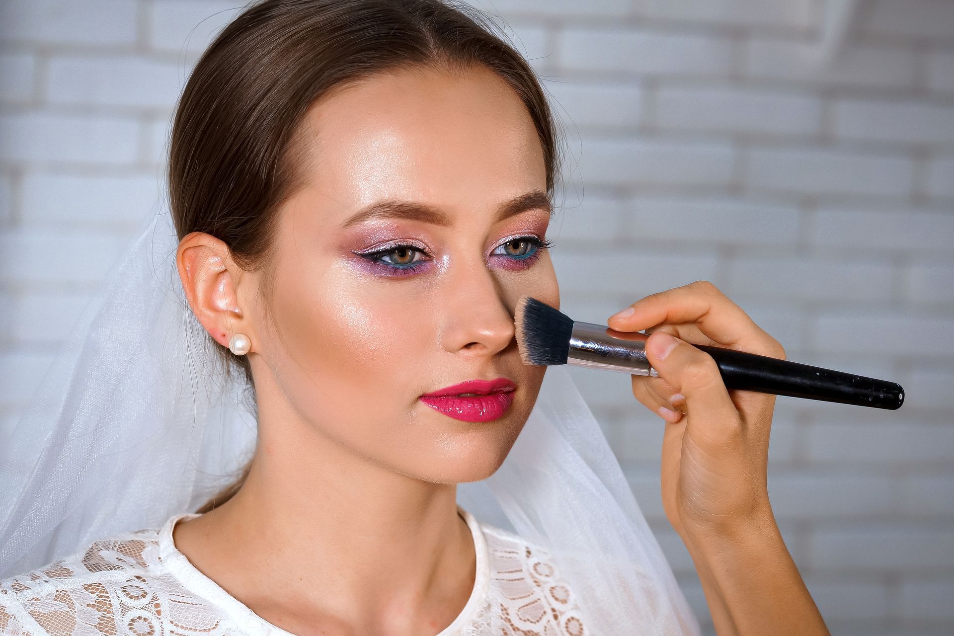 A woman is getting her makeup done by a makeup artist.