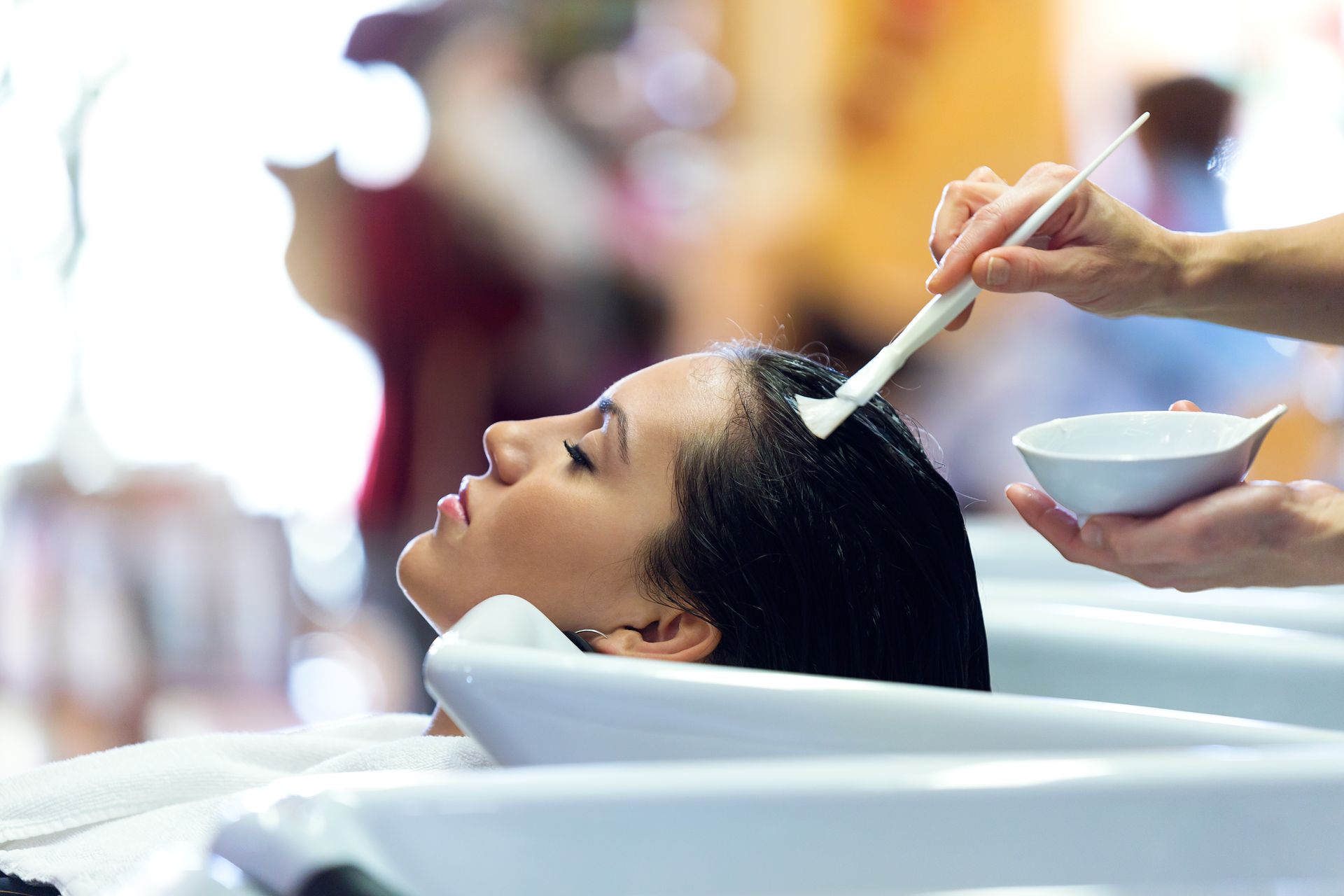 A woman is getting her hair washed in a sink at a salon.