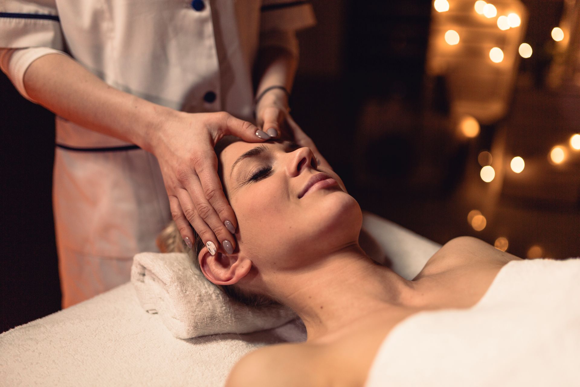 A woman is getting a head massage at a spa.