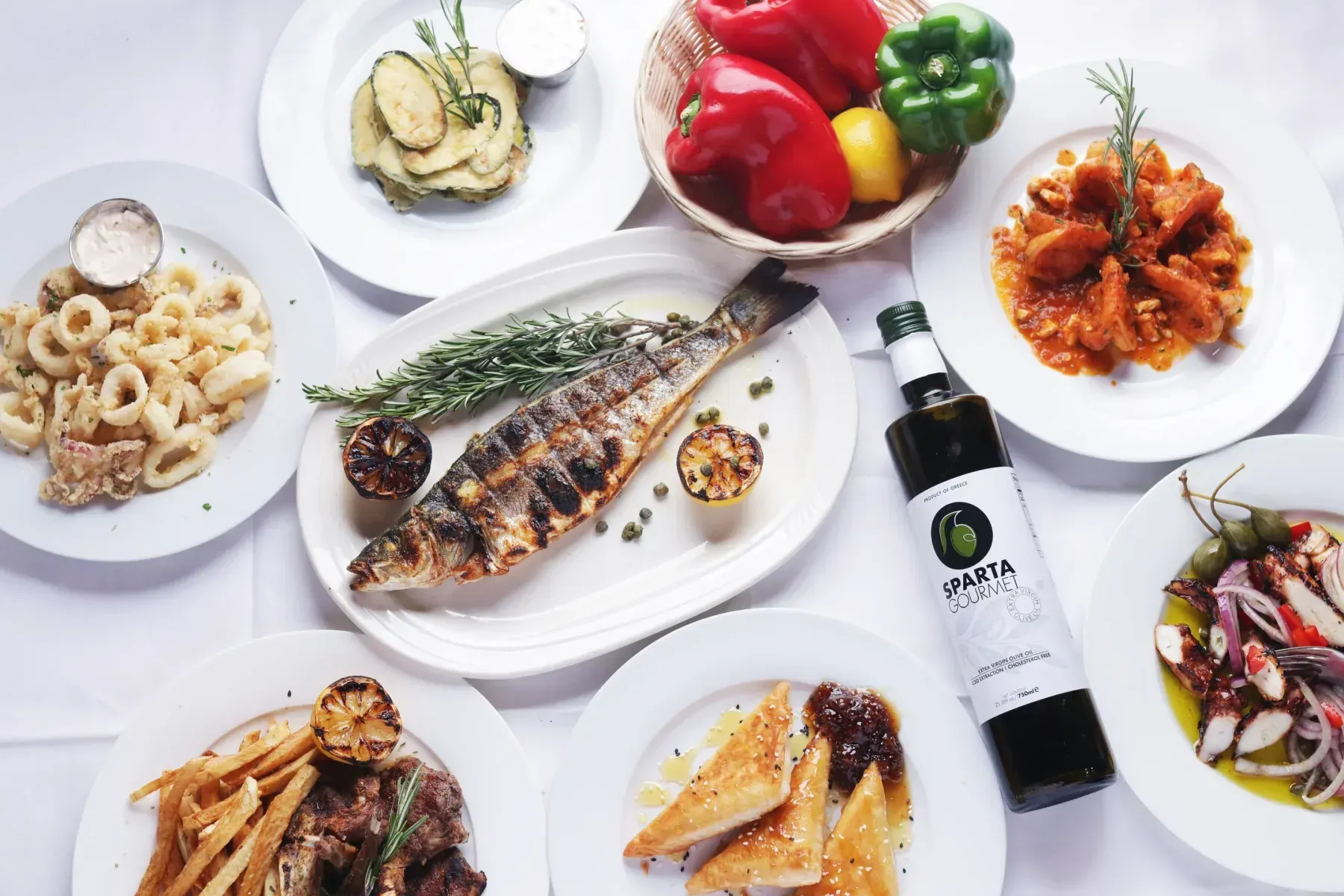 A table topped with plates of food and a bottle of olive oil