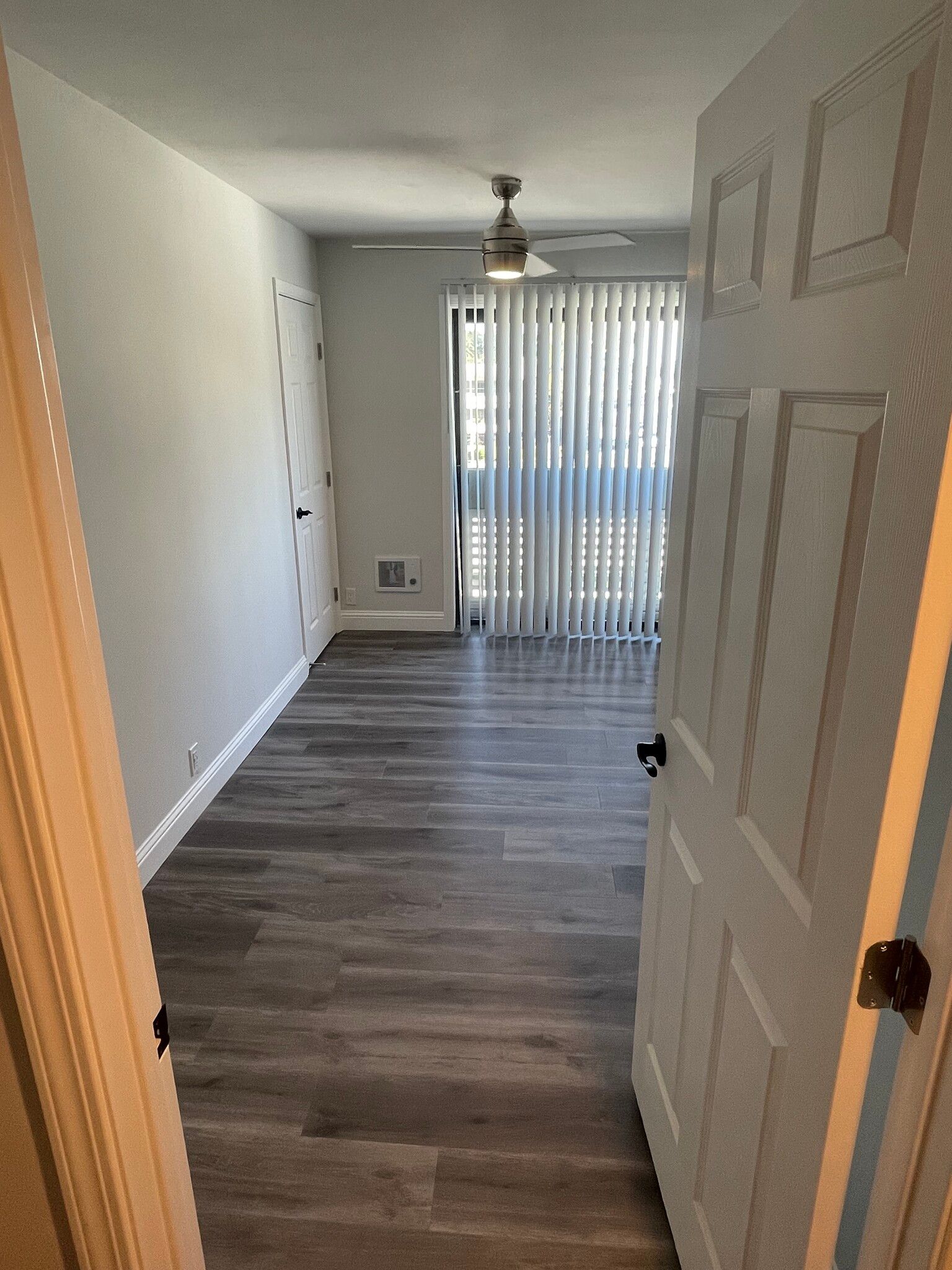 A door is open to a living room with hardwood floors and a ceiling fan.