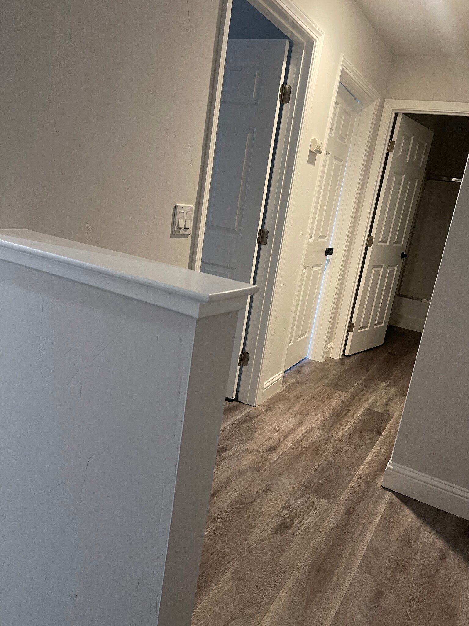 A hallway with hardwood floors and white doors in a house.