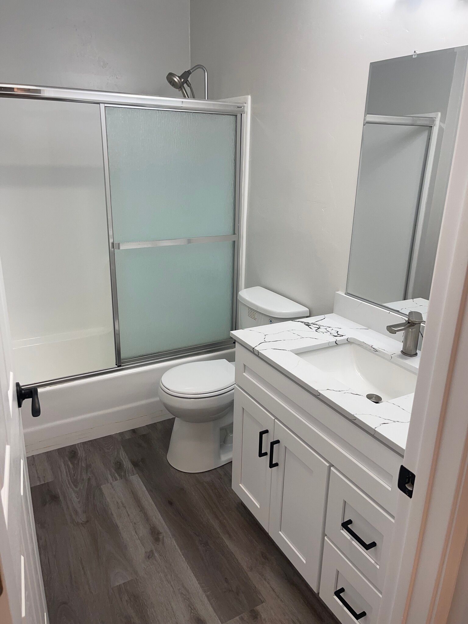 A bathroom with a toilet , sink , shower and mirror.