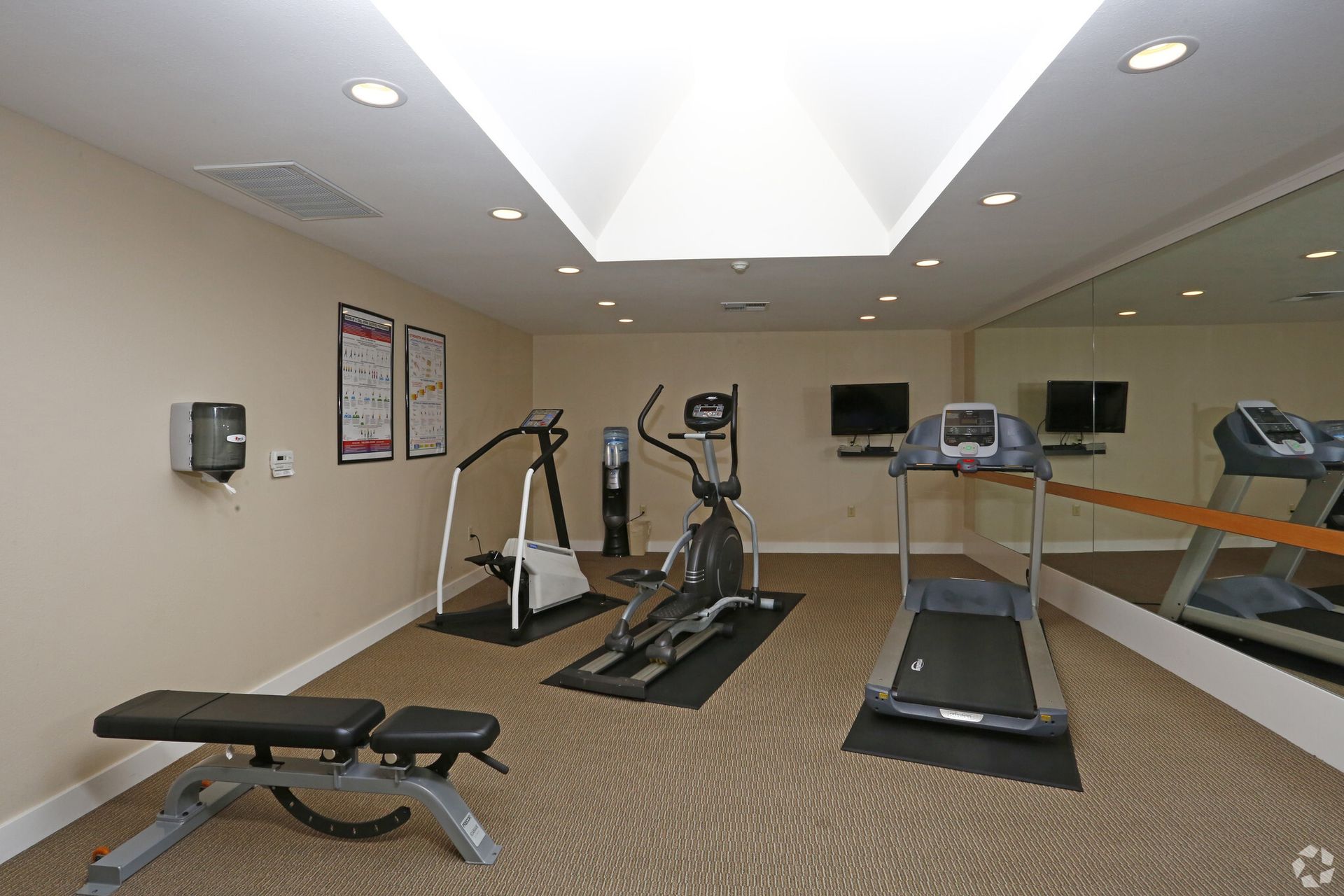 A gym with treadmills , exercise bikes and a bench