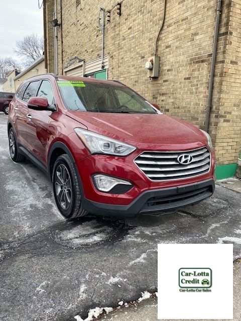 Red Hyundai Santa Fe parked on pavement in front of a brick building.