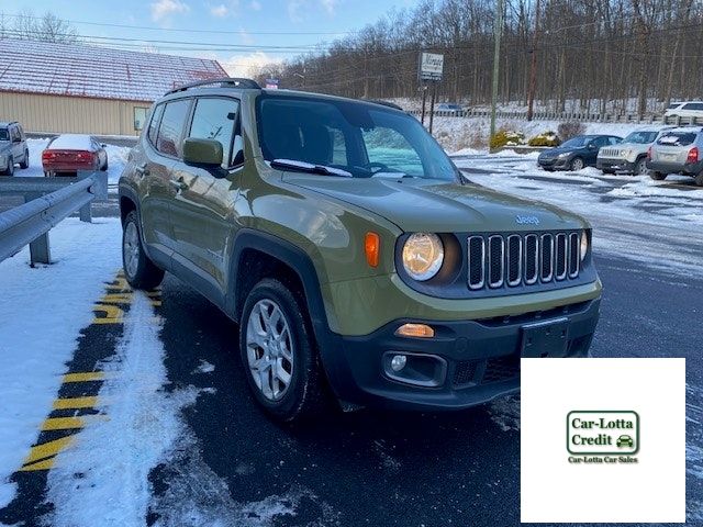 Green Jeep Renegade parked on snow next to a curb. 