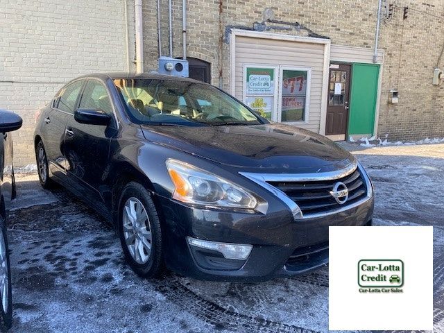 Dark sedan parked outside a car lot on a snowy day.
