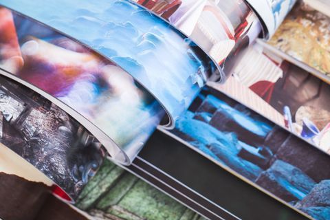 Supporti di stampa arrotolati con varie immagini colorate, tra cui blu, rosso e toni scuri.