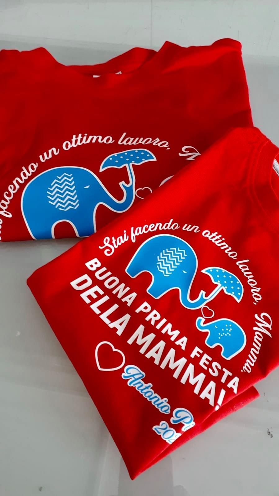 Magliette rosse con scritte bianche in italiano, elefanti blu con ombrelli, cuori. 