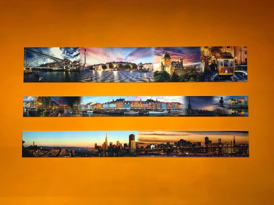 Tre panorami urbani montati su una parete arancione.