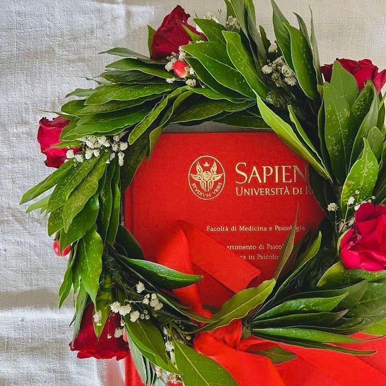 Pila di libri blu scuro con scritte dorate su una superficie di legno chiaro.