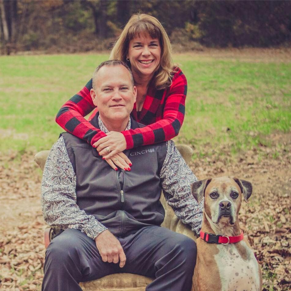 A man and woman are posing for a picture with their dog