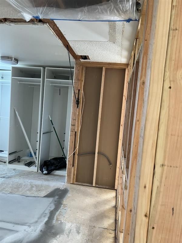 Room under renovation with exposed studs, drywall, and closet fixtures. Room under renovation with exposed studs, drywall, and closet fixtures.