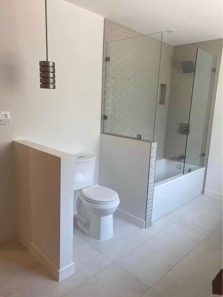 Modern bathroom with white walls, toilet, shower, and pendant light fixture. Modern bathroom with white walls, toilet, shower, and pendant light fixture.