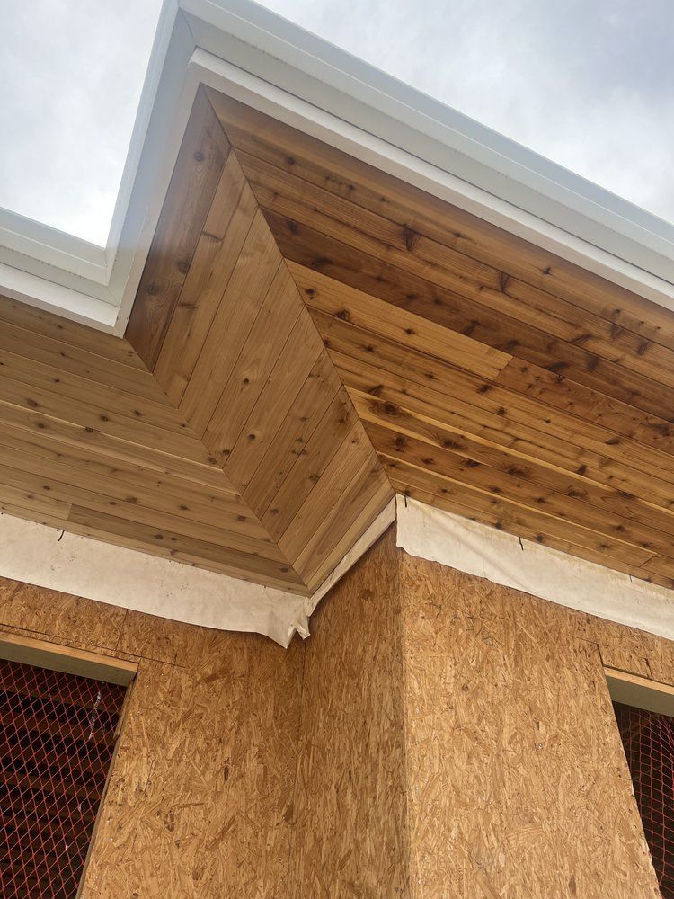 Corner of building under construction; cedar soffit and OSB sheathing visible.
