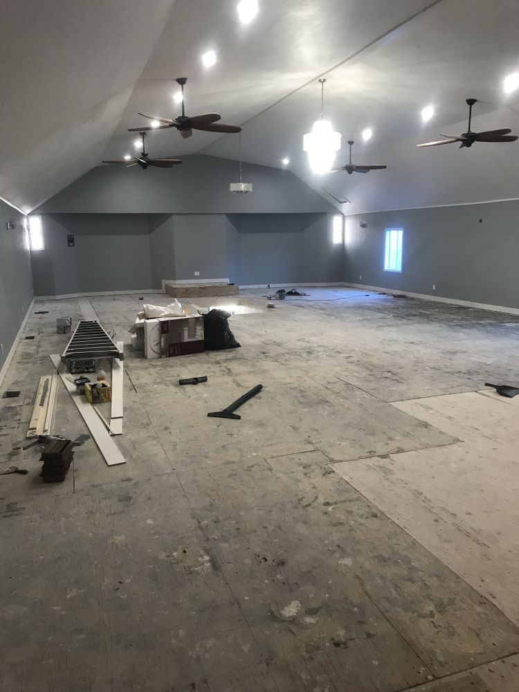 Two-car garage with dark gray doors and windows. Beige house with stone accents on sunny day. Two-car garage with dark gray doors and windows. Beige house with stone accents on sunny day.