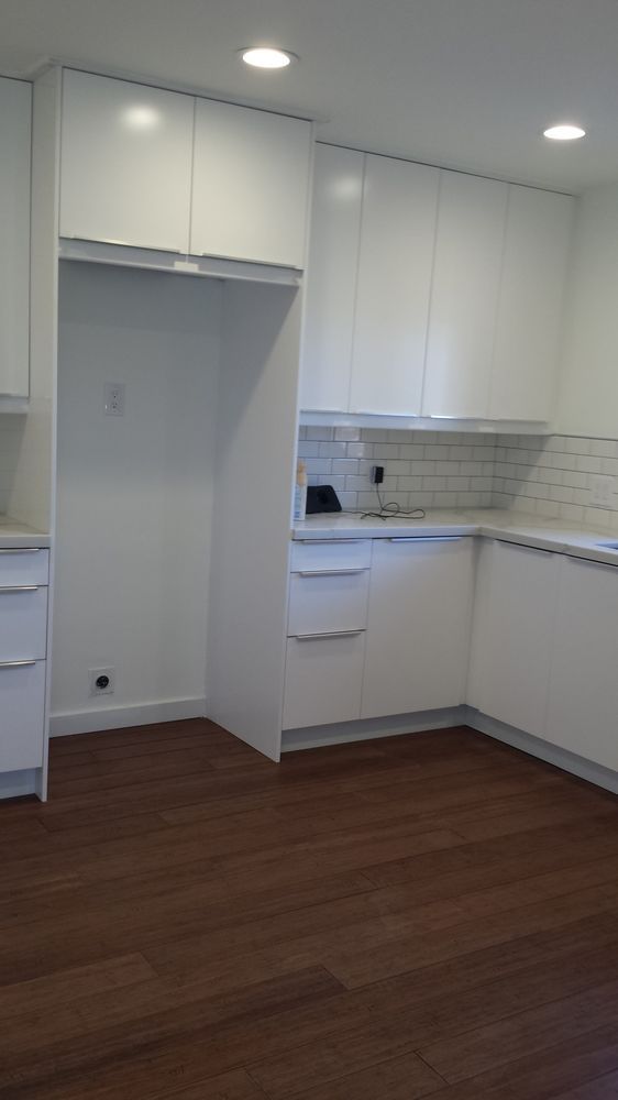 White kitchen with dark wood floors and built-in refrigerator.