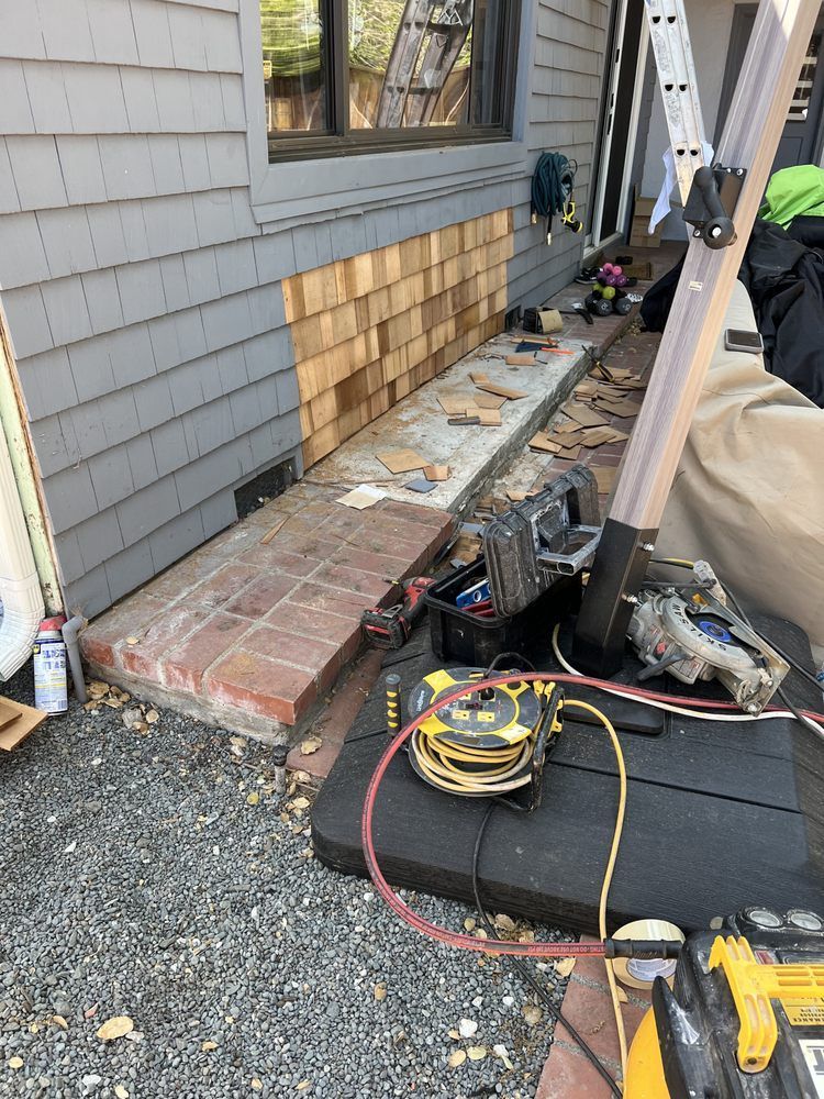 Construction: Replacing siding on a house. Tools, ladder, and exposed wood siding visible. Construction: Replacing siding on a house. Tools, ladder, and exposed wood siding visible.
