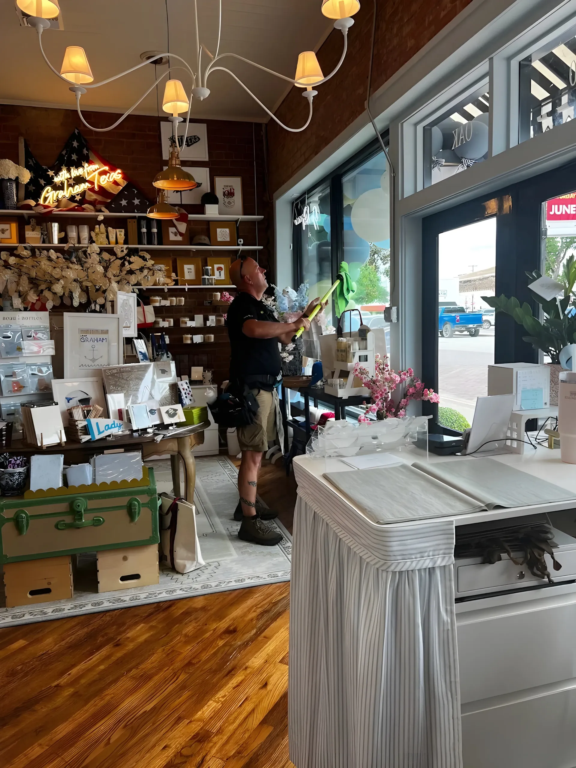 Cozy shop interior with shelves of gifts, hanging lights, and a person arranging items near the front window