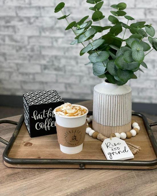 A wooden tray with a cup of coffee and a plant on it.