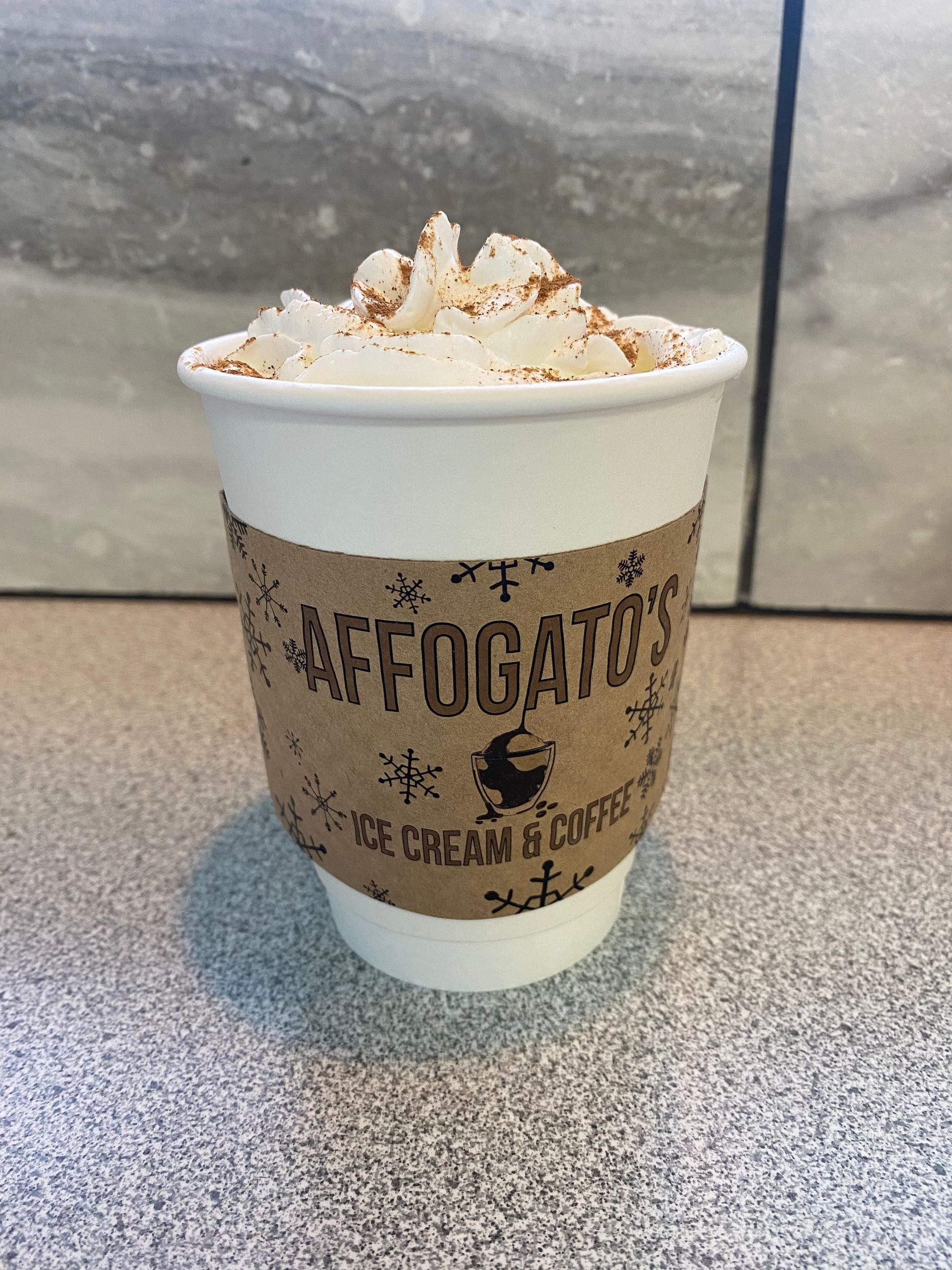 A cup of hot chocolate with whipped cream on top is on a table.