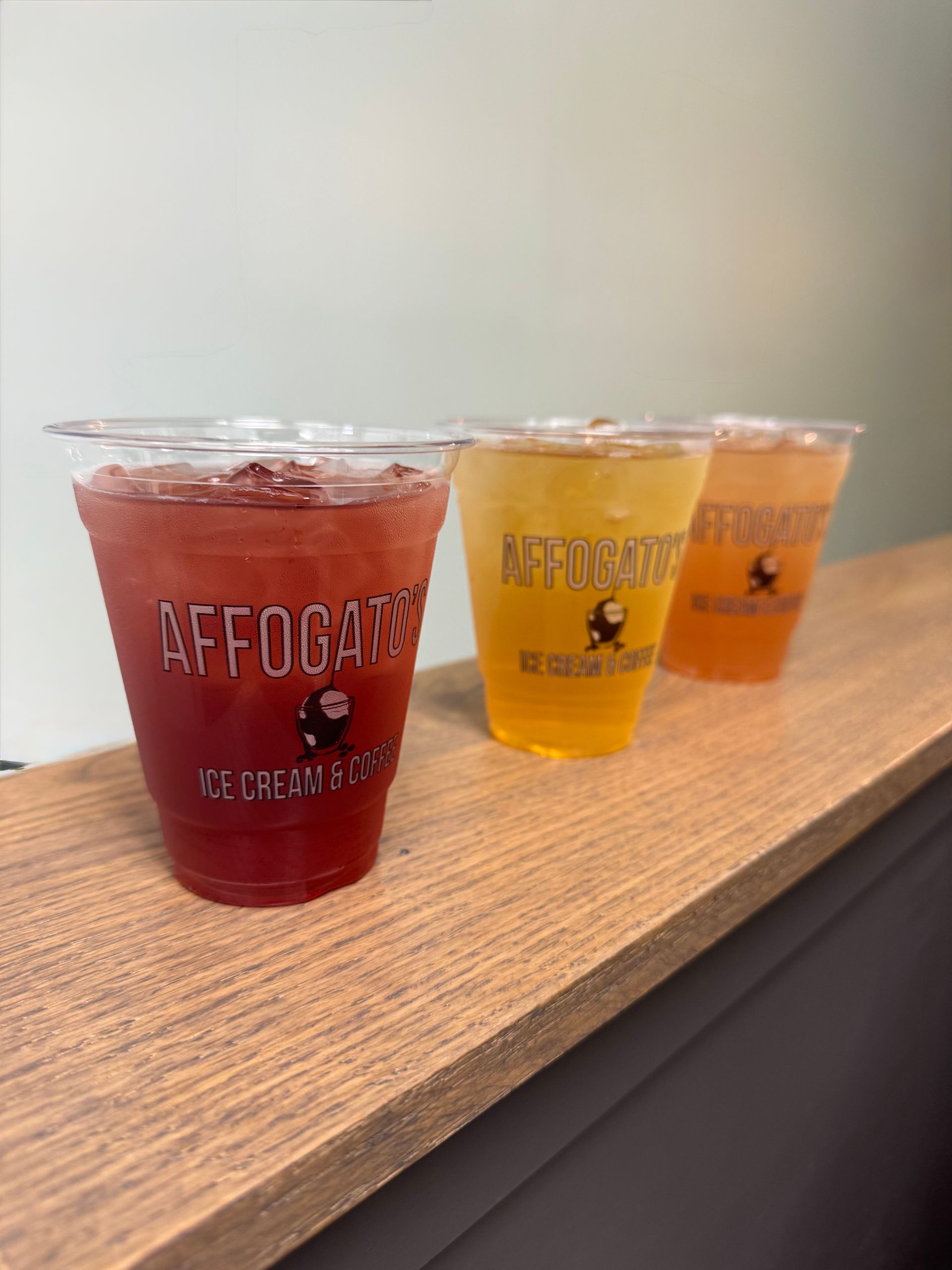 Three cups of drinks are sitting on a wooden table.