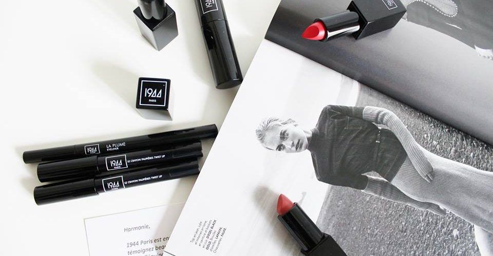 Une photo en noir et blanc d'une femme allongée sur une table avec du rouge à lèvres, des stylos et un magazine.