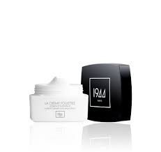 Un pot de crème blanc à côté d'une boîte noire sur une surface blanche.