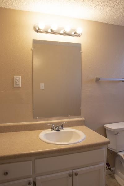 Bathroom vanity with sink, mirror, and light fixture above a beige countertop.