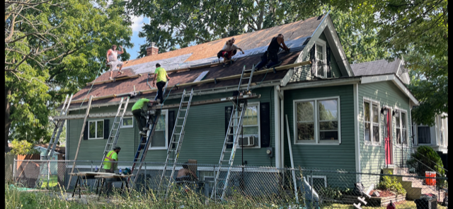 A group of people are working on the roof of a house.