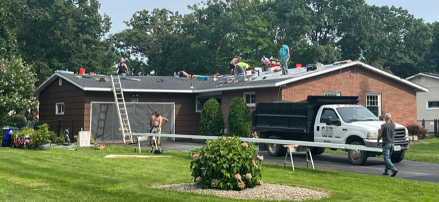 A group of people are working on the roof of a house.