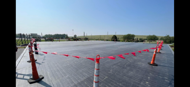 A row of orange and white traffic cones are lined up on the side of a road.