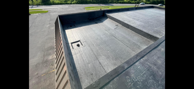 A black commercial roof with a hole in the middle of it.