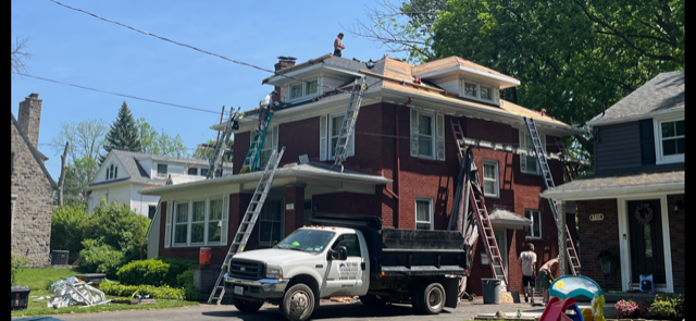 A white truck is parked in front of a brick house.