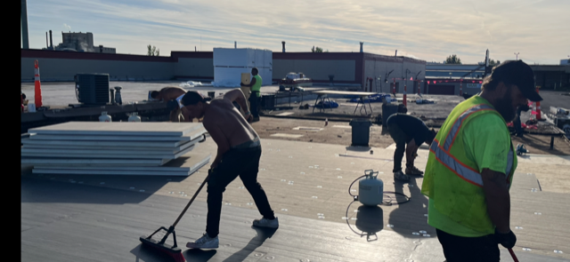 A group of construction workers are working on a roof.