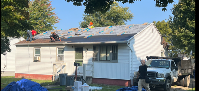 A group of people are working on the roof of a house.