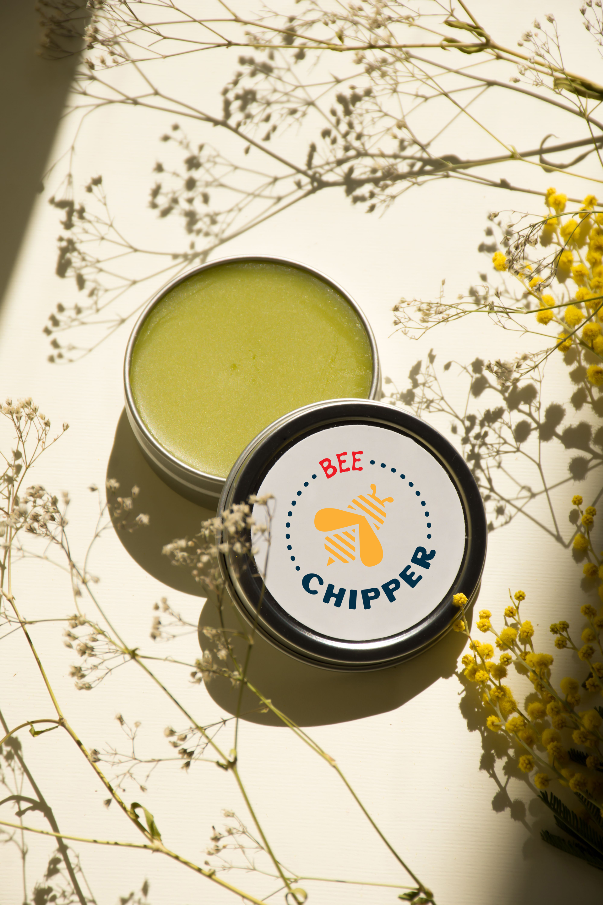 Open green balm tin with a label that says 