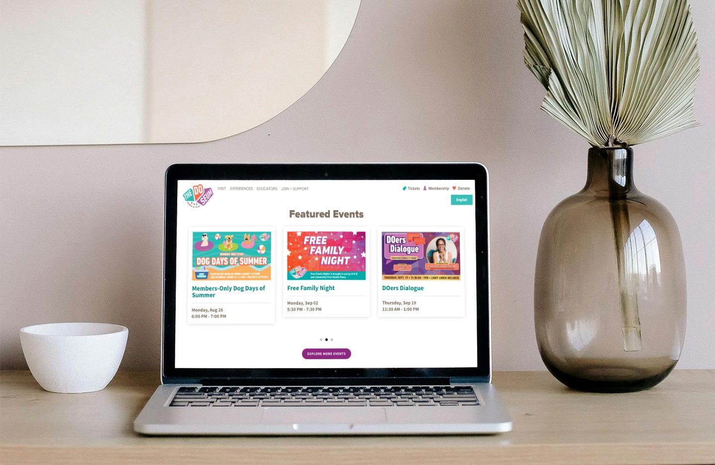 Laptop displaying website with featured deals, beside vase and bowl.