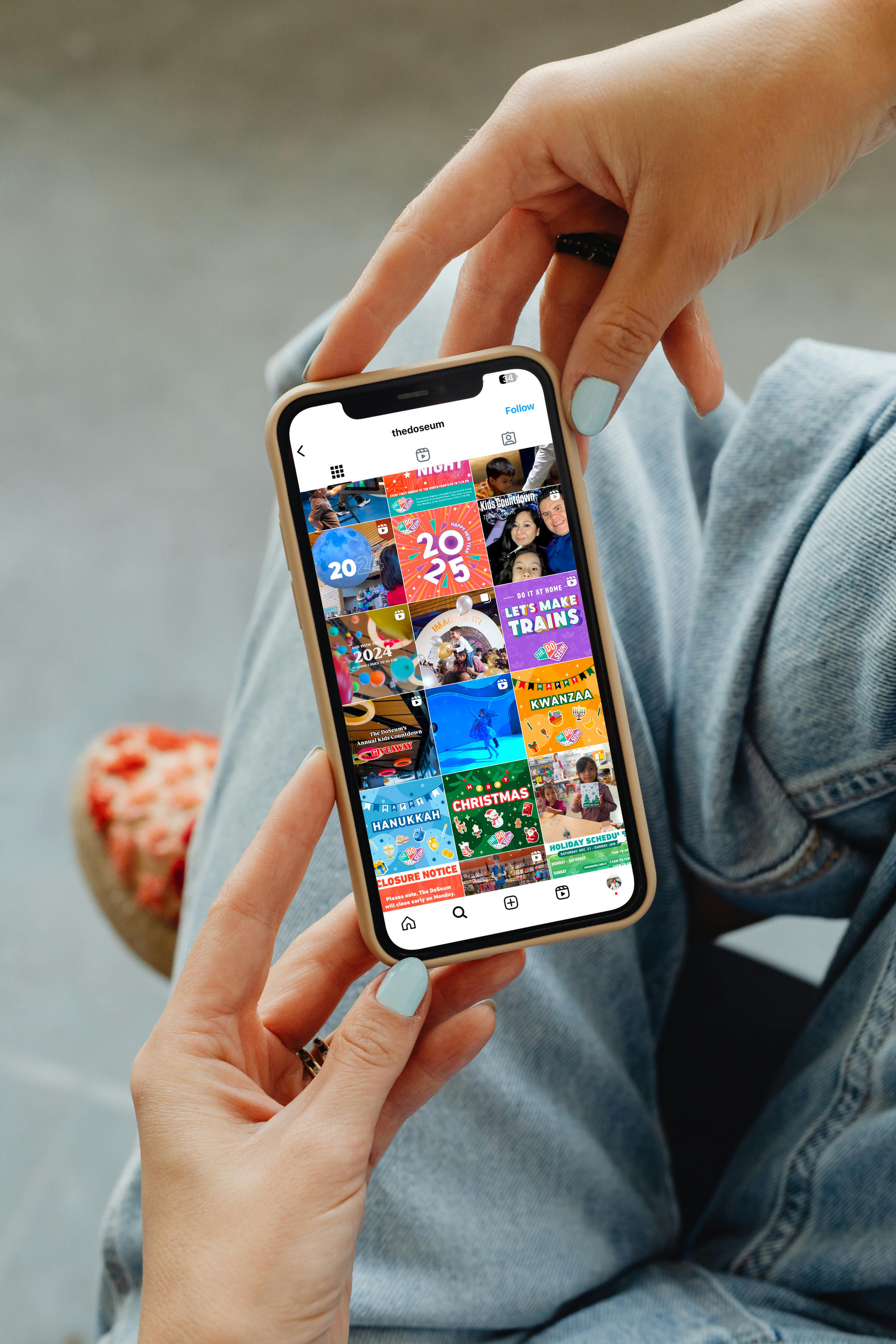 Person holding a smartphone displaying a grid of colorful thumbnails, possibly social media posts.