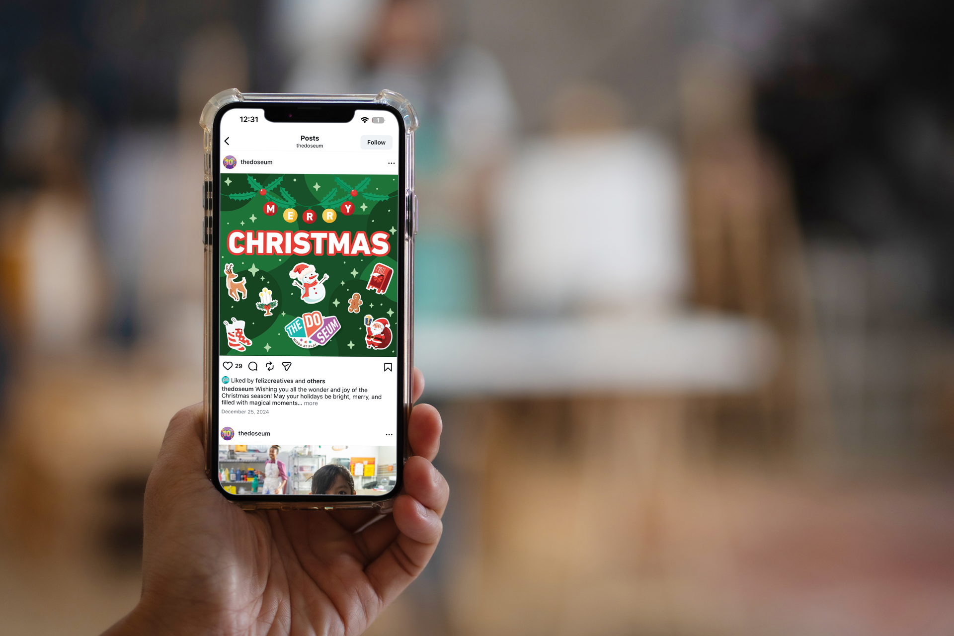 Hand holding a phone displaying a Christmas-themed social media post with various festive graphics.