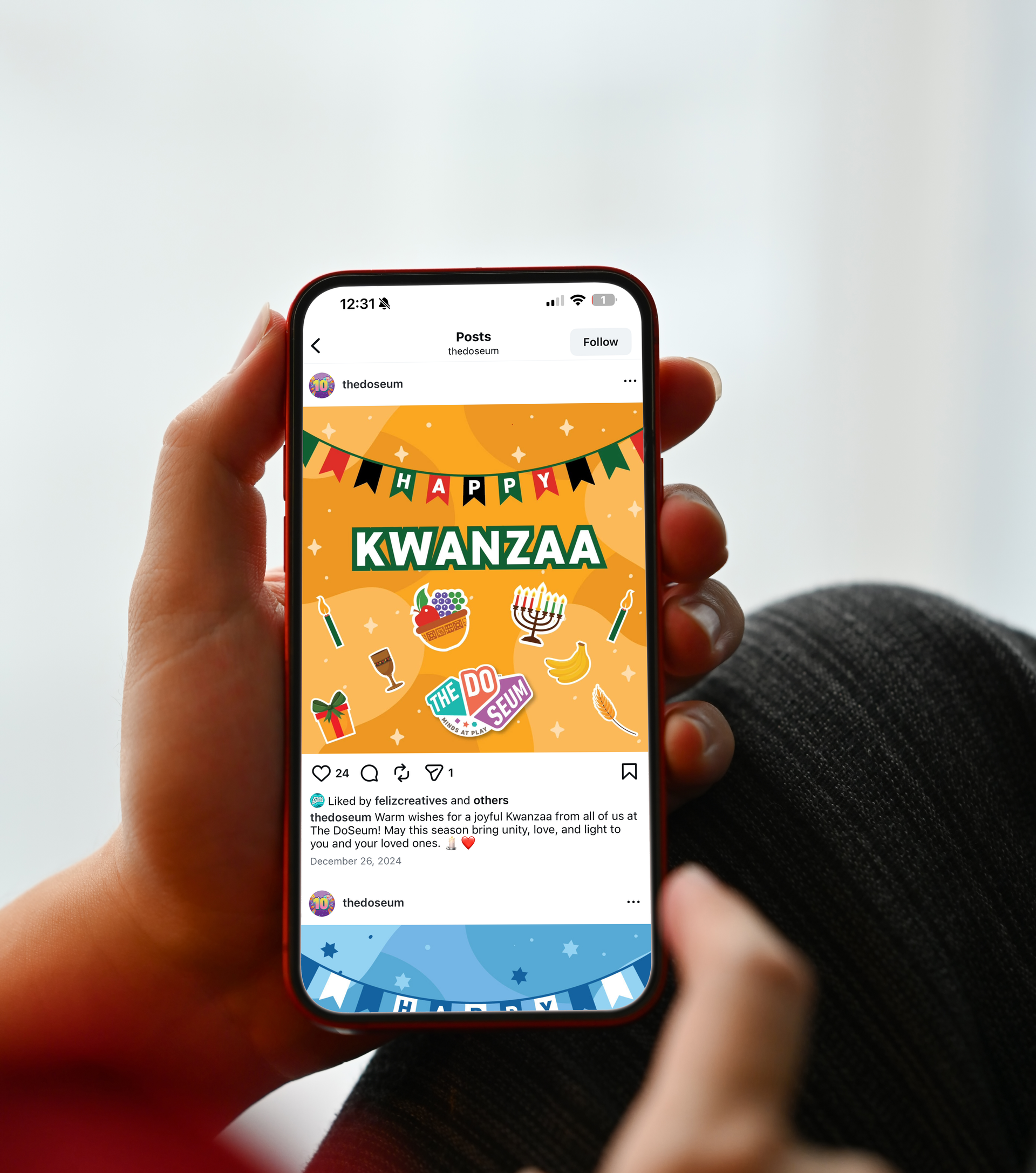 Person holding phone with Kwanzaa social media post, colorful graphic, black, green, and red banner.