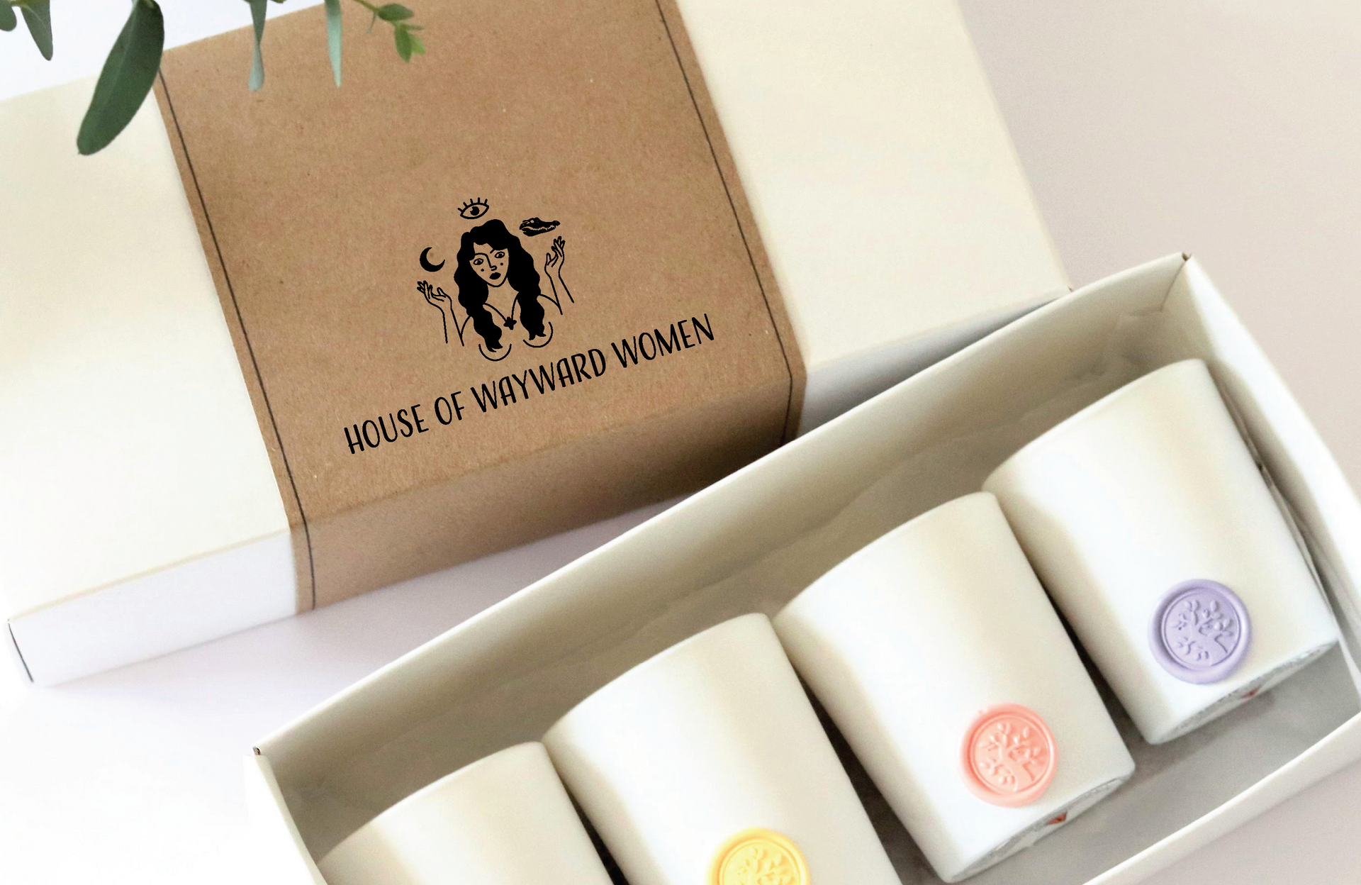 Gift box with four white House of Wayward Women candle holders, each with a colored wax seal.