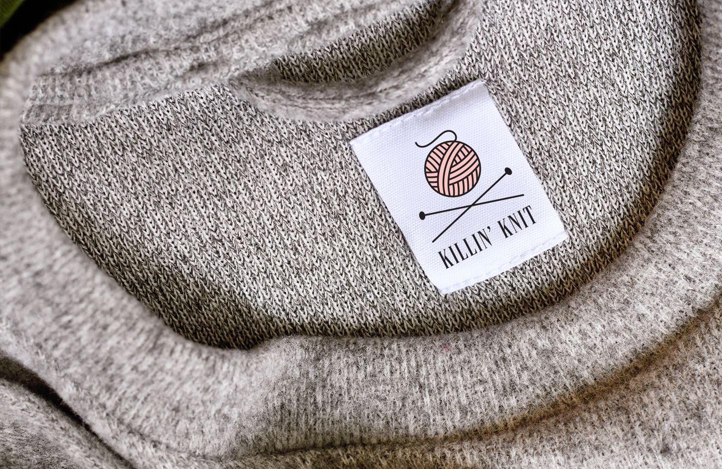 Killin' Knit tag on a gray sweater with a yarn ball logo and 