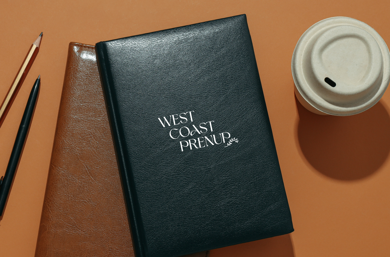 Black and brown leather journals with pens and coffee cup on a tan surface.