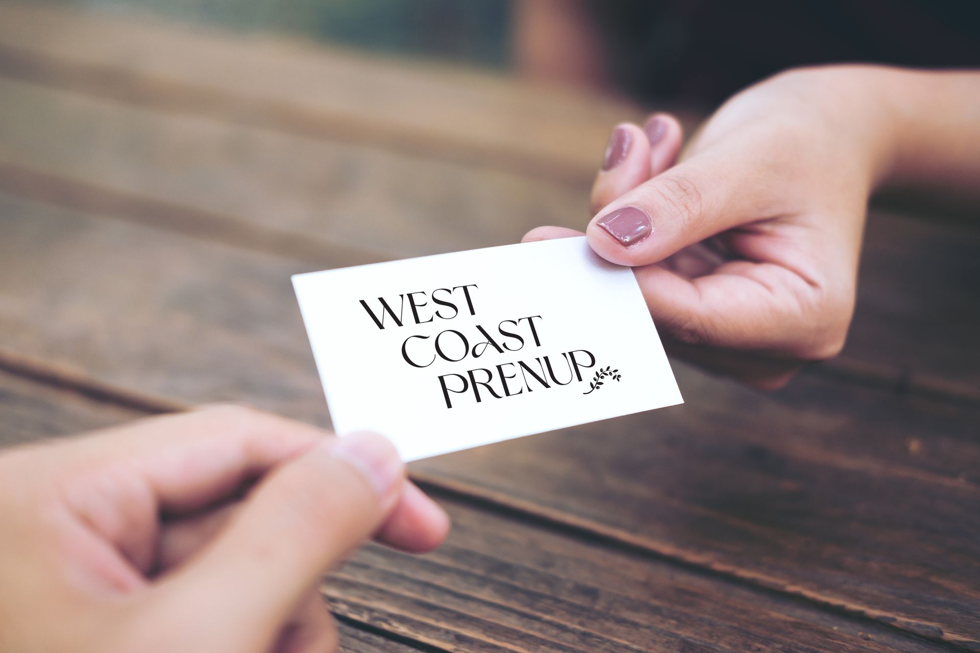 Hands exchanging a business card that reads 
