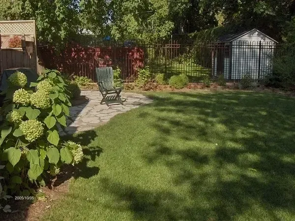 Une cour arrière avec cabanon, chaises et patio.